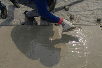 Motion blur cement surface on the ground is being smoothed with steel trowel in hands