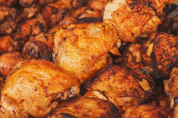 A large juicy grilled piece of pork meat on a skewer cooked on a charcoal grill. Baked meat on a street market counter with shallow depth of field. Food meat texture background.