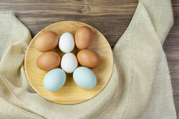 Various shapes, colors, and sizes of eggs with sackcloth on wooden background.