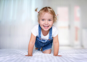 Child girl playing on a bed.Happy smiling girl indoors.Caucasian kid in bedroom.