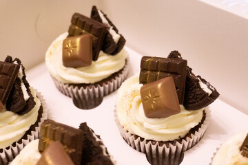 Cupcakes with cream cheese on a green background. Tasty cupcakes with golden chocolate decor. Homemade tasty food. 