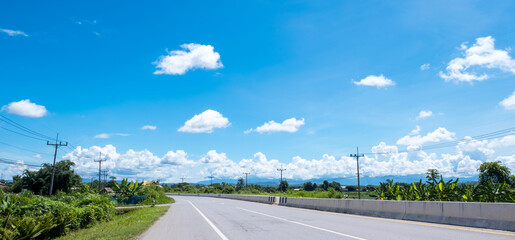 Beautiful landscape, white clouds, blue sky, mountains and long asphalt roads into the countryside