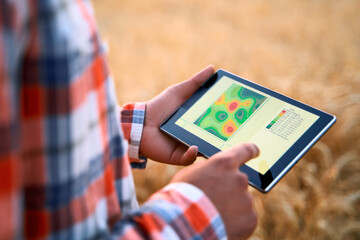 Precision farming. Farmer hands hold tablet using online data management software, differential...