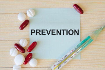  text prevention written on a blue background near tablets and a thermometer. medicines