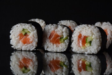 Salmon rolls or Maki-zushi. on black background with reflection