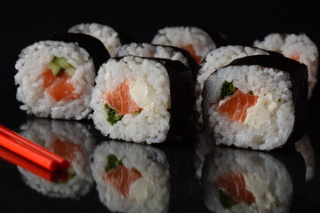 Salmon rolls or Maki-zushi. on black background with reflection