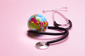 Stethoscope World globe and protective mask concept on a pink