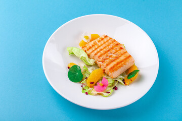 Grilled salmon fillet steak with salad garnish in white plate