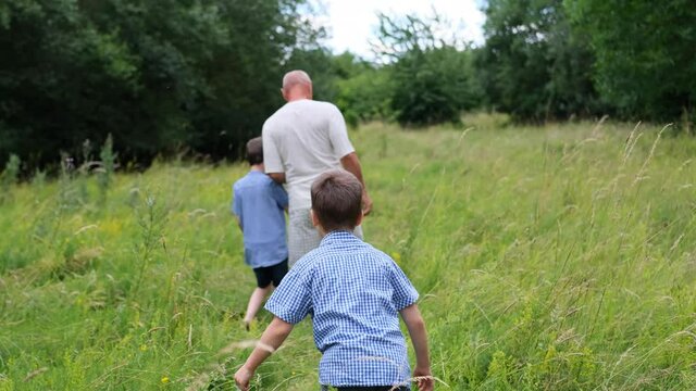 family, man and children walk among meadows and forests in summer, the concept of family summer vacations, picnics, vacations, camping, activity in the park