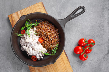 Beef stroganoff in cream and buckwheat and cherry tomatoes in pan