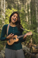 Happy Beautiful Woman Playing the Ukelele and singing a song in the middle of a forest