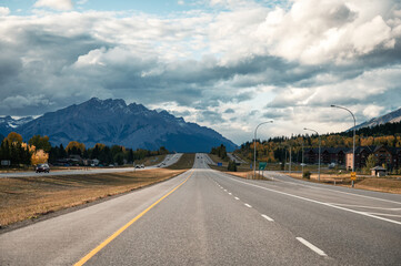 Car driving on highway with rocky mountains in autumn at Canmore