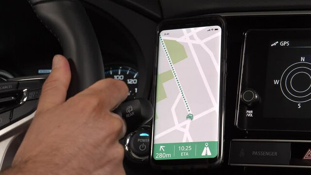 Mobile phone being used by a vehicle driver as a GPS showing a map to navigate. Smartphone app concept mounted on the dashboard of the car.