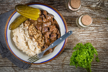 Beef stew served with barley and pickled cucumber.