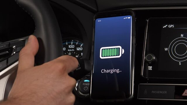 Mobile phone being plugged to a car having its battery charged. Charging smartphone connected to a vehicle.