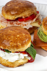 Assortment of homemade scones with ham, cheese, avocado, salmon, cream cheese and strawberry jam