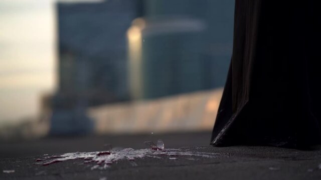 red wine glass is breaking on floor near feet of woman, closeup view