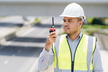 Portrait engineer handsome man or architect looking construction with the command of a radio. and white safety  helmet in construction site.