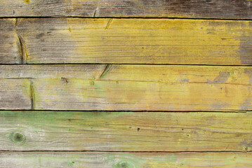 Old tumbledown weathered wood boards background with peeled paint, shabby rustic multicolored barn timbered siding aged withered faded gray surface.