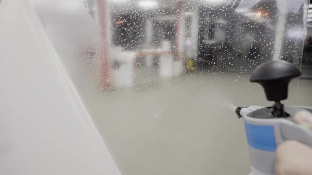 Close-up of spraying plastic paint protection film with liquid slip solution before applying it to a car.