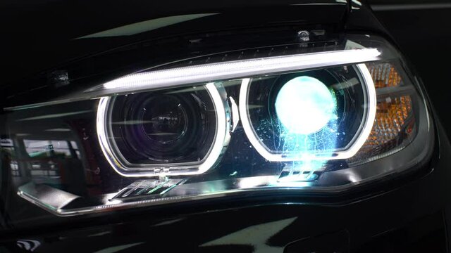 Close-up of a car headlight turning on and then adjusting the aim of the light.