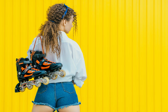 Young sexy girl with beautiful buttoks holding rollers on yellow background