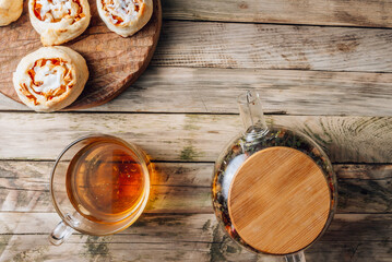 Rolled buns with apple and coconut paste on wooden cutting board with herbal tea. Quick puff pastry for breakfast.