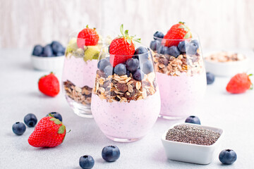 Superfoods layered pudding with granola, blueberry and strawberry in glasses. Yogurt with chia seeds, berries, kiwi and muesli for healthy breakfast, copy space. Perfect for summer snack or dessert