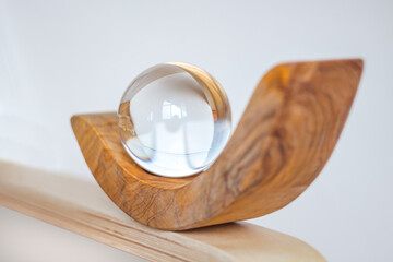 Crystal,glass ball.Wine stand made of olive wood.Light gray background. Interior detail, home design subject. Balance. 