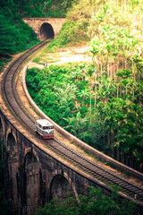 Scenic Train Ride over the world renowned demodara nine arches bridge. Service Car buggy train coming out of the ella tunnel in the morning light through beautiful lush green and tea estates.