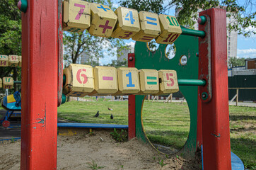 Fototapeta na wymiar Large wooden cubes with colorful numbers on a street playground. Children's games and outdoor training. Early child development, learning arithmetic.