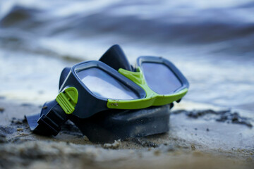 mask for diving lies on the sand, the shore against the background of the wave