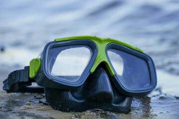 mask for diving lies on the sand, the shore against the background of the wave