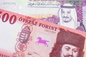 A close up image of a red, one hundred Hungarian forint bill close up with a colorful five riyal note from Saudi Arabia in macro