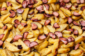 Fried potatoes and smoked sausages baked in the oven at home, very tasty but not healthy food