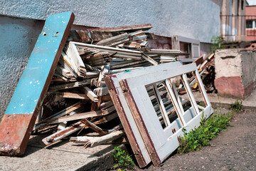 Old windows and doors lie on the street as garbage for recycling, new windows and doors are inserted in the building, so the old wooden ones will be recycled