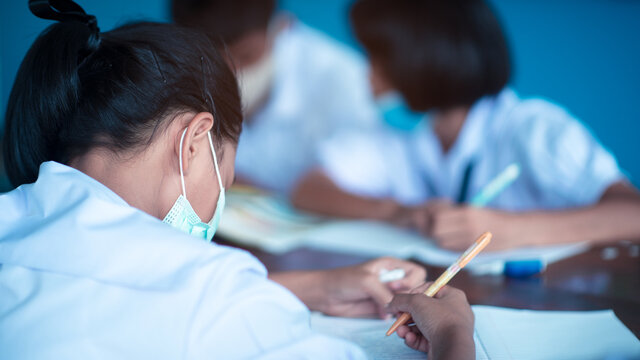 Uniform students wearing hygienic mask while studying in the classroom