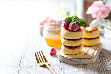 Cheesecakes with honey and raspberries. Traditional Russian sweet pancakes. Healthy breakfast. Homemade food