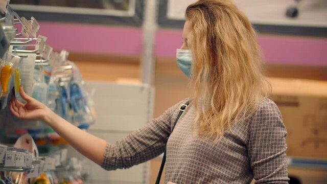 Woman Shopper Choosing Product In Hypermarket Store.Girl In Face Mask Shopping In Market On Covid19 Coronavirus Pandemic Quarantine Lock down. Bayer In Medical Mask In Supermarket Avoid Self Distance