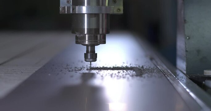 Milling machine cuts a part from a sheet of plastic, shavings fly. CNC factory machine. Close-up