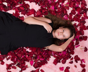 Obraz na płótnie Canvas Young girl lies with rose petals, studio fashion shot