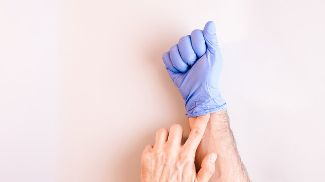 Image 6 of a sequence of images in which a man's hands taking off blue disposable gloves medical. Top view. Selective focus