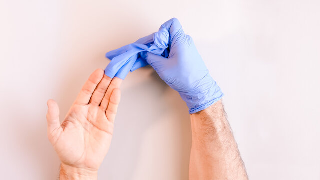 Image 4 of a sequence of images in which a man's hands taking off blue disposable gloves medical. Top view. Selective focus