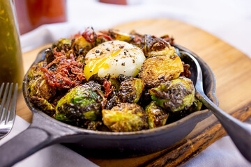 A view of caramelized Brussels sprouts served in a cast iron skillet, in a restaurant or kitchen setting.