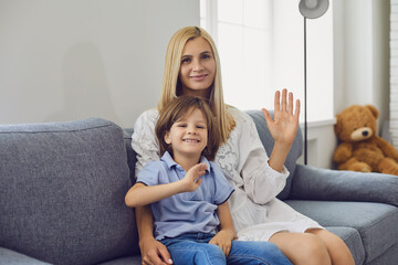 Online communication. Mother and her son talking to family from home. Parent and child looking at camera and waving