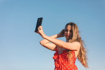 Beautifulgirl makes a selfie outdoors in a summer sunset