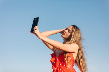 Beautifulgirl makes a selfie outdoors in a summer sunset
