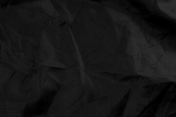 Wrapping black material with wrinkles and wrinkled folds. Old crumpled synthetic fabric. Abstract dramatic background. For design and headlines.