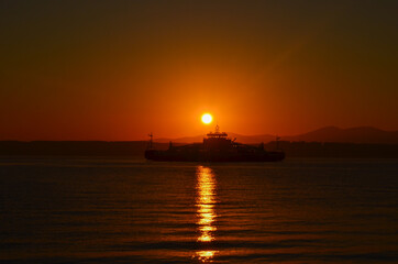 Fototapeta na wymiar Canakkale with a sunrise and a steamer, morning hours, red colors, sunrise, orange, red, yellow colors 