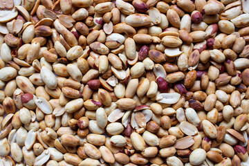 Roasted peanuts and peeled top view as background.